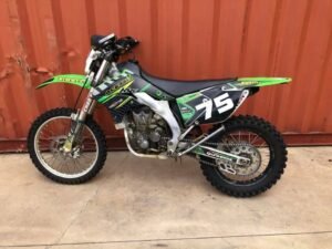 Green Kawasaki dirt bike with number 75 graphics
